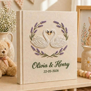 Personalized embroidered wedding photo album with swan embroidery, lavender wreath, custom names, wedding date, and linen hardcover design