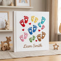 Personalized hand embroidered photo album featuring colorful baby footprints with heart details and custom baby name on linen cover