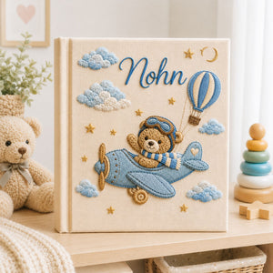 Personalized hand embroidered photo album featuring a teddy bear pilot flying a vintage airplane with hot air balloons, clouds and stars