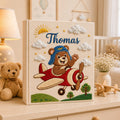 Personalized hand embroidered baby photo album with teddy bear pilot flying a vintage airplane surrounded by clouds and sunshine