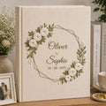 Personalized embroidered wedding photo album with white roses geometric floral wreath and custom couple names on linen cover