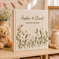 Personalized embroidered wedding photo album with white daisy flowers, botanical greenery embroidery, custom couple names, wedding date, and elegant linen hardcover design