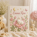 Personalized hand embroidered photo album featuring a sleeping bunny resting on a large pink flower surrounded by blossoms, butterflies, stars, and a crescent moon on a premium linen cover customized with a baby name