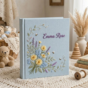 Personalized hand embroidered photo album featuring a wildflower bouquet with lavender, daisies, delicate greenery, bees, and custom name embroidery on a blue linen cover