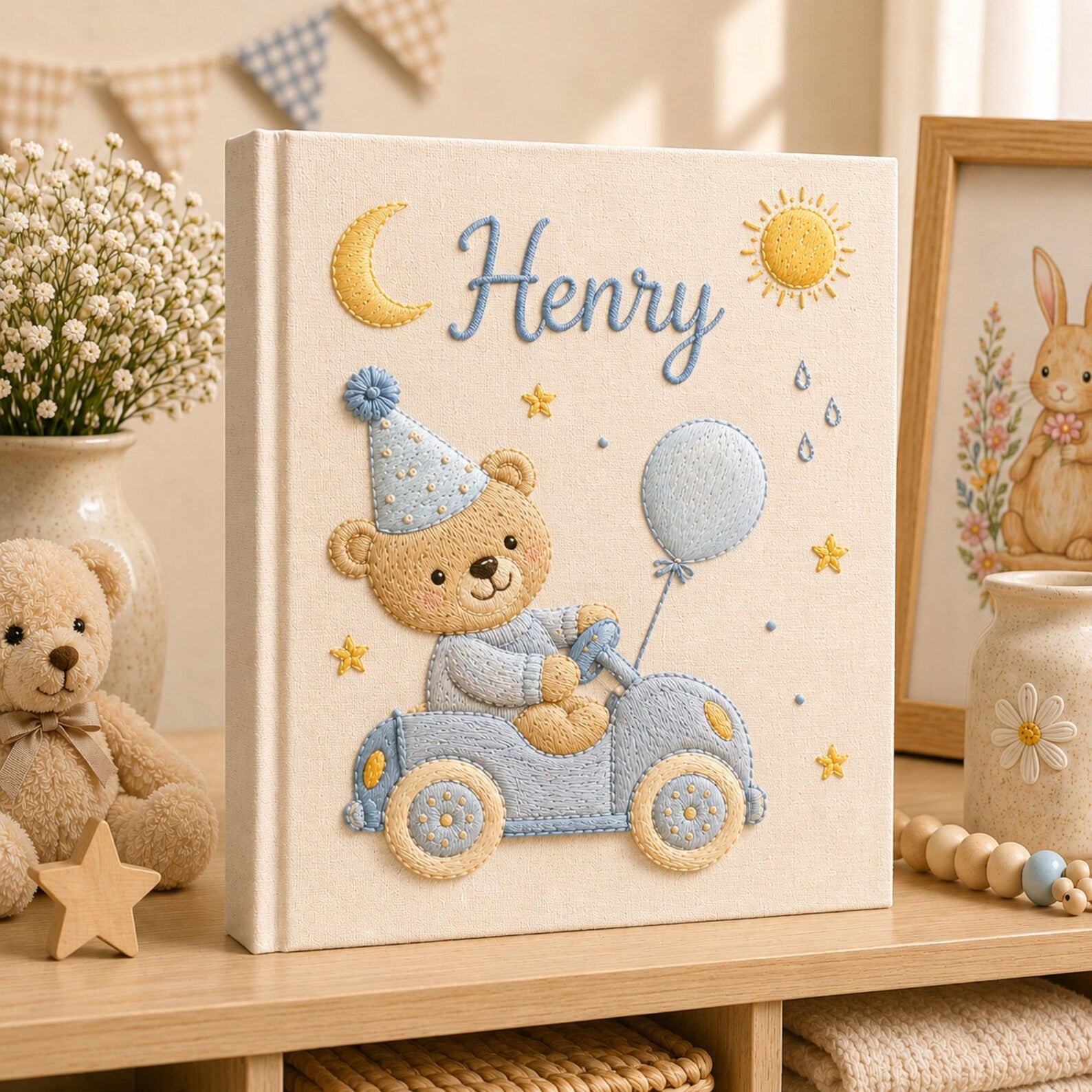 Personalized hand embroidered baby photo album featuring teddy bear driving a pastel blue vintage car with balloon, moon, stars, and sunshine accents