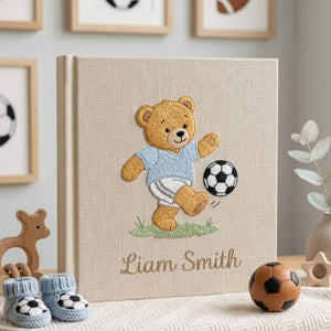 Personalized hand embroidered photo album featuring a teddy bear playing soccer with a football and custom baby name on linen cover