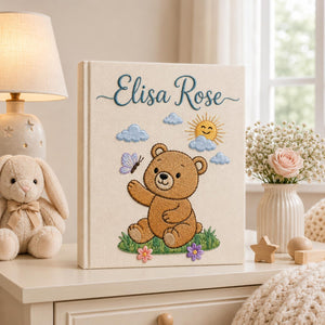 Personalized embroidered baby photo album featuring teddy bear, sunshine, clouds, flowers, and butterfly design