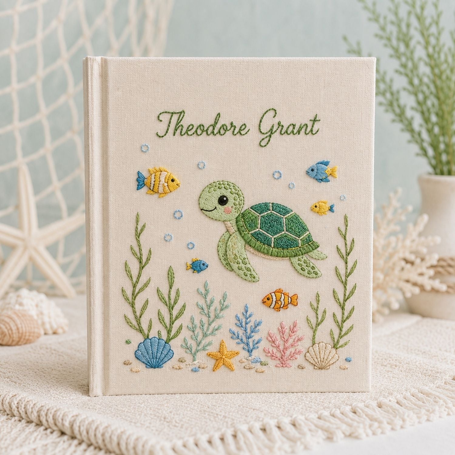 Personalized hand embroidered photo album featuring a cute sea turtle swimming with tropical fish, coral, seashells, and ocean plants on a premium linen cover customized with a baby name