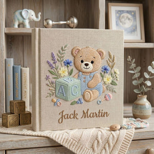 Personalized hand embroidered photo album featuring teddy bear in blue overalls with alphabet block and floral details on linen cover