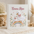Personalized hand embroidered photo album featuring a swan mother and baby standing on a pastel rainbow surrounded by daisies and floral details