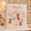 Personalized hand embroidered photo album featuring woodland animals with pastel balloons, clouds, stars, and rainbow details on a linen cover