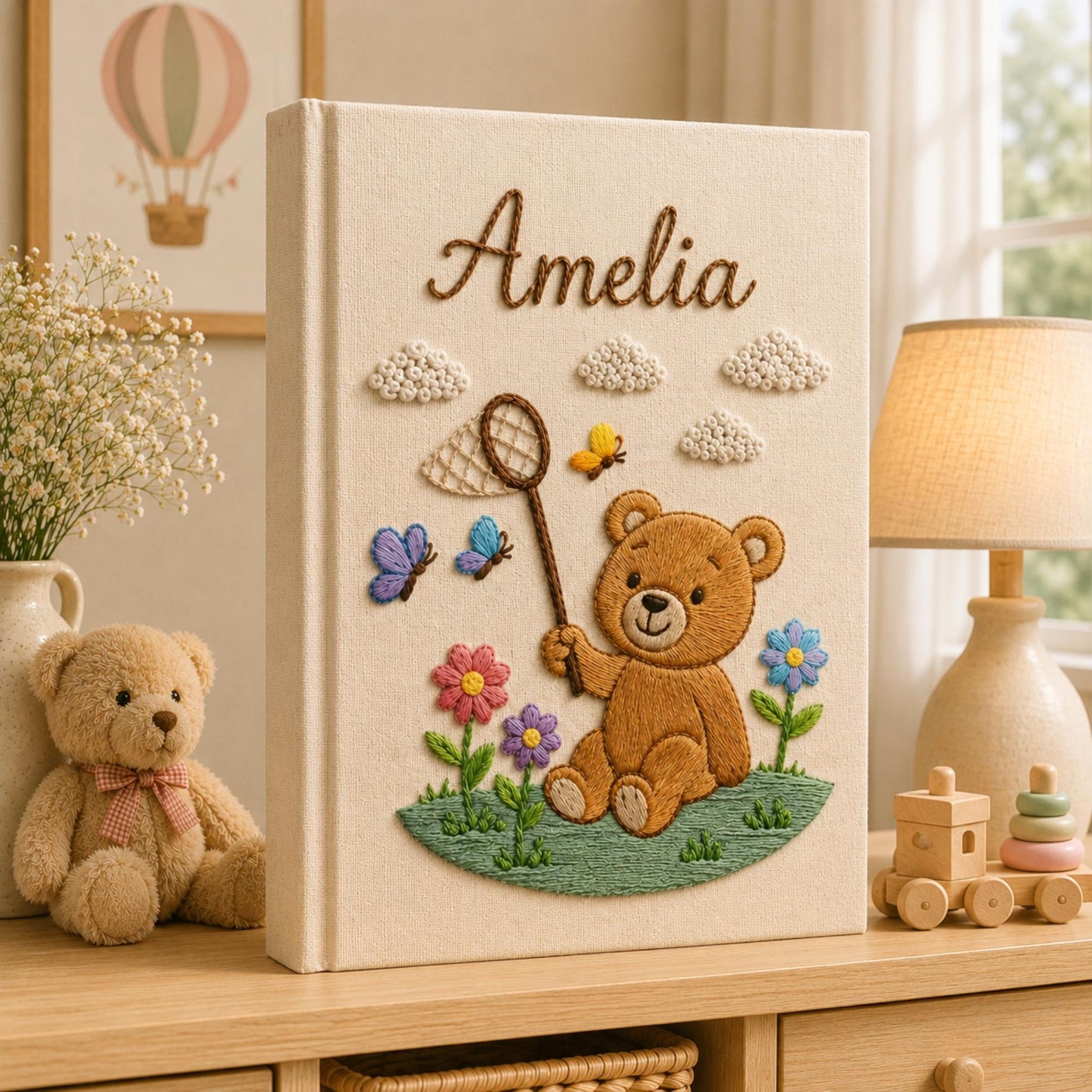 Personalized embroidered baby photo album featuring teddy bear holding butterfly net surrounded by flowers and butterflies