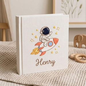 Personalized hand embroidered baby photo album with astronaut riding rocket and stars nursery design