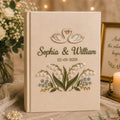 Personalized embroidered wedding photo album with swan embroidery, lily of the valley flowers, botanical details, custom couple names, wedding date, and elegant linen hardcover design