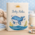 Personalized hand embroidered photo album featuring a smiling blue whale above ocean waves with sunrise details on a linen keepsake cover