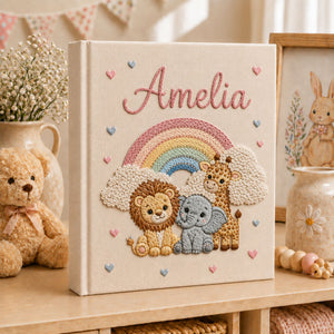 Personalized hand embroidered photo album featuring lion elephant and giraffe under a pastel rainbow with custom name embroidery