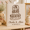 Personalized embroidered wedding photo album with tiered wedding cake embroidery, bride and groom silhouette design, custom couple names, wedding date, and elegant linen hardcover
