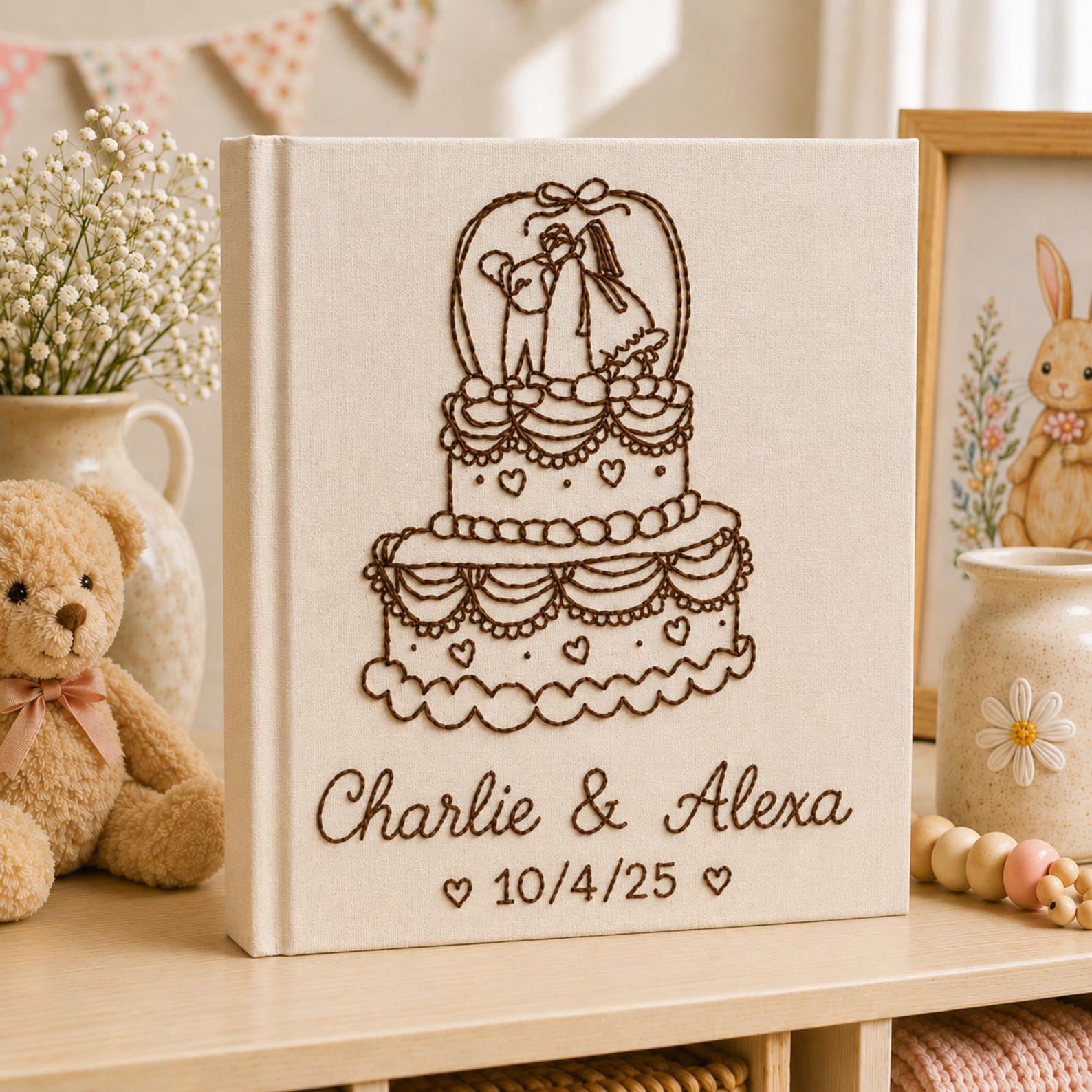 Personalized embroidered wedding photo album with tiered wedding cake embroidery, bride and groom silhouette design, custom couple names, wedding date, and elegant linen hardcover