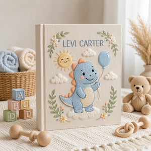 Personalized hand embroidered photo album featuring a cute blue dinosaur holding a balloon with sunshine and cloud details on a linen cover