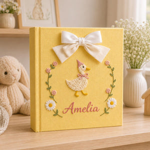 Personalized yellow hand embroidered baby photo album with cute duckling, floral wreath, and ribbon bow