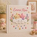 Personalized hand embroidered photo album featuring smiling stars resting on fluffy clouds with hanging pastel stars and floral accents on a premium linen cover customized with a baby name