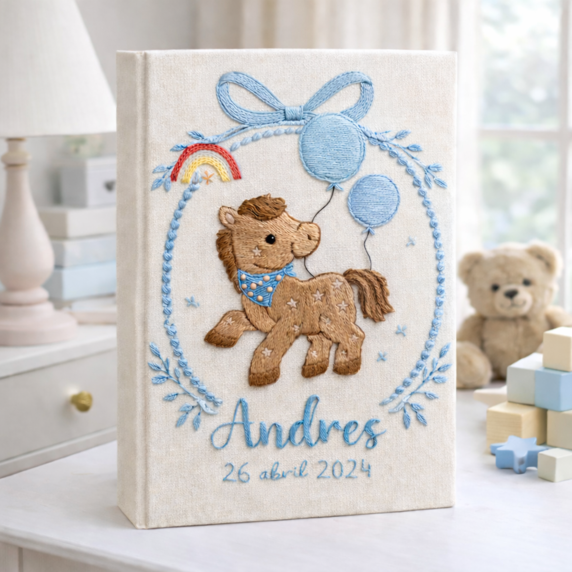 Personalized hand embroidered photo album featuring an adorable pony with balloons, colorful rainbow, fluffy clouds, and custom name embroidery on linen cover