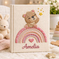 Personalized hand embroidered baby photo album featuring teddy bear sitting on pastel rainbow with stars and heart accents