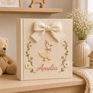 Personalized yellow hand embroidered baby photo album with cute duckling, floral wreath, and ribbon bow
