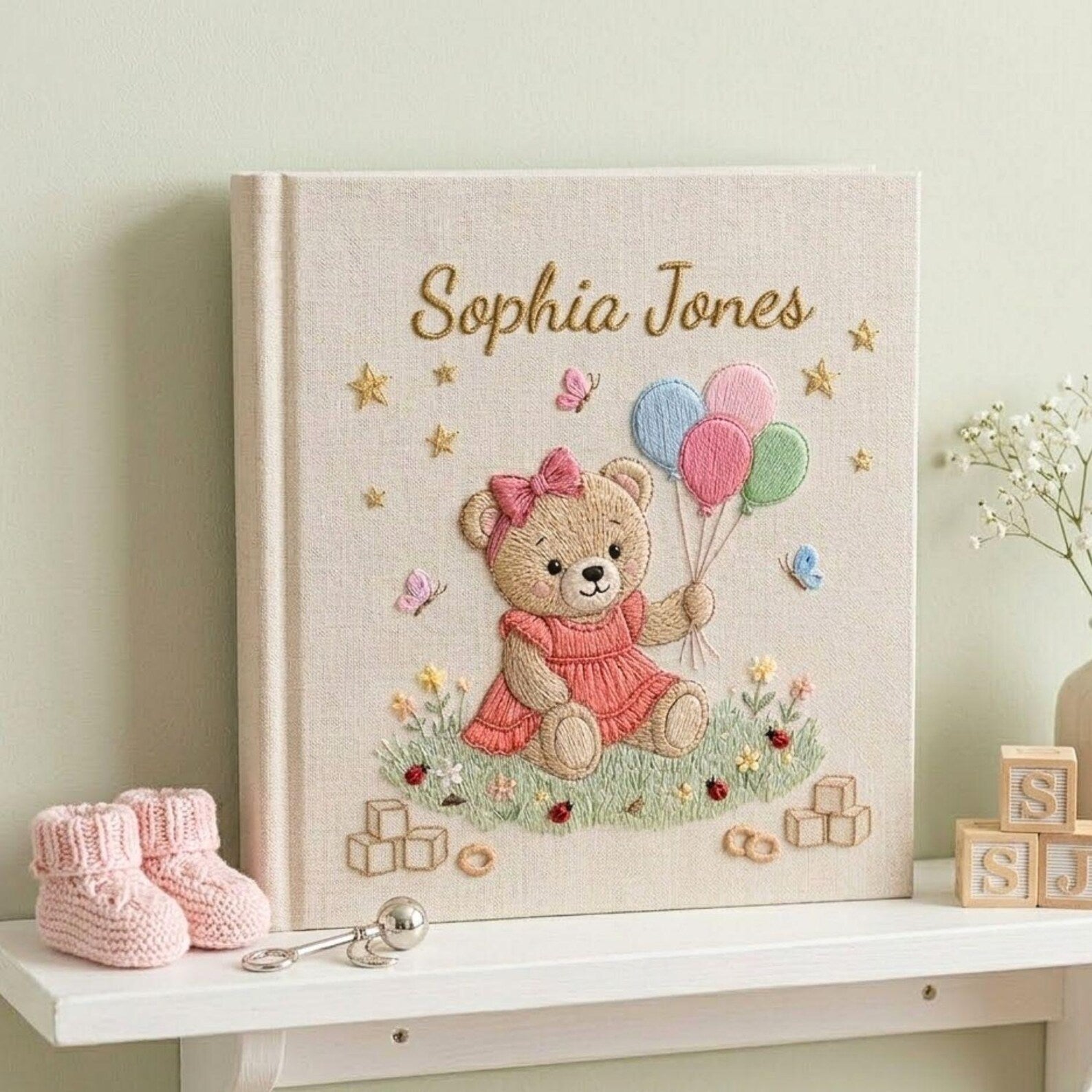 Personalized hand embroidered photo album featuring teddy bear holding pastel balloons surrounded by flowers butterflies and custom baby name