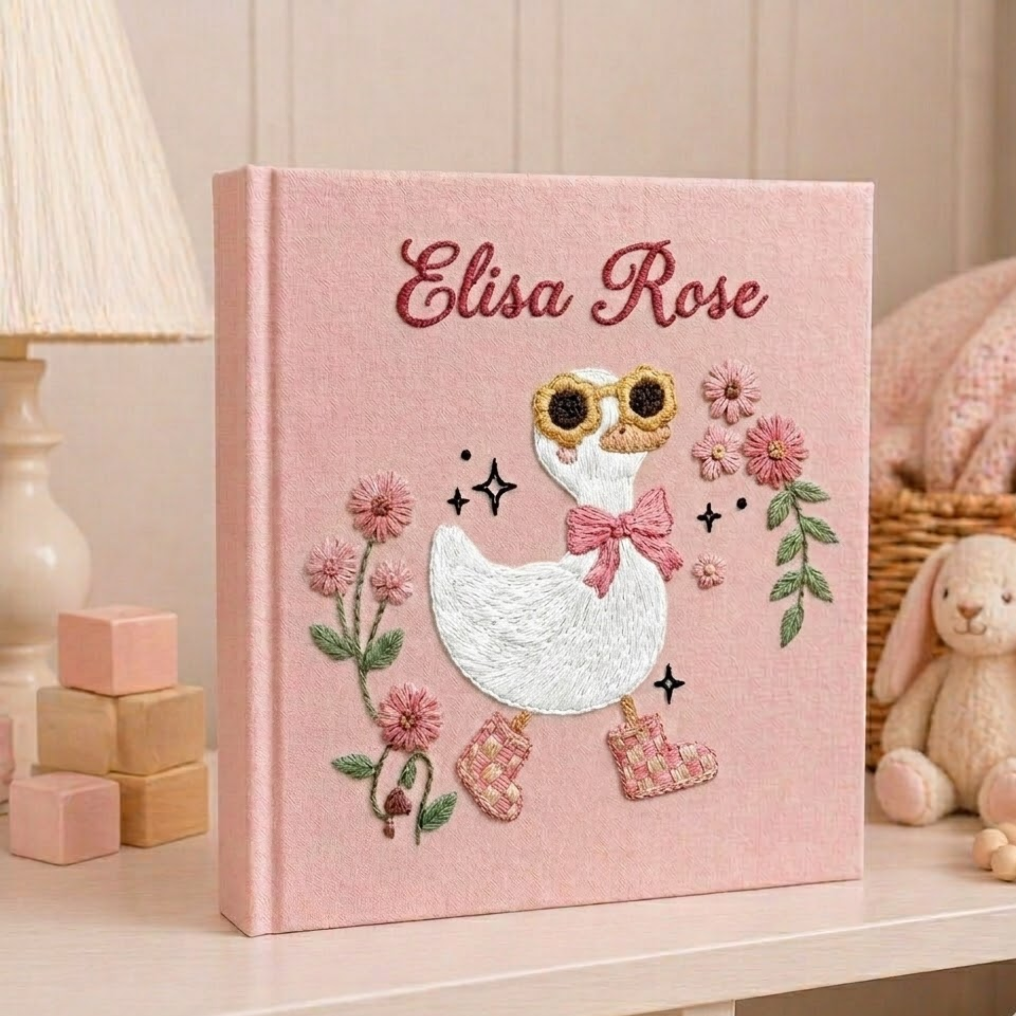 Personalized hand embroidered photo album featuring a charming goose girl with bow, flowers, and cottagecore details on a pink linen cover