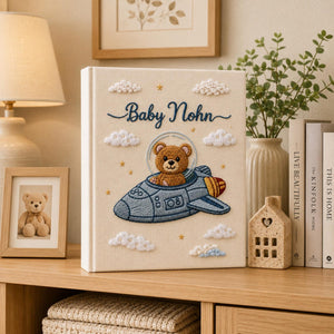 Personalized embroidered baby photo album featuring teddy bear astronaut riding a space rocket with fluffy clouds