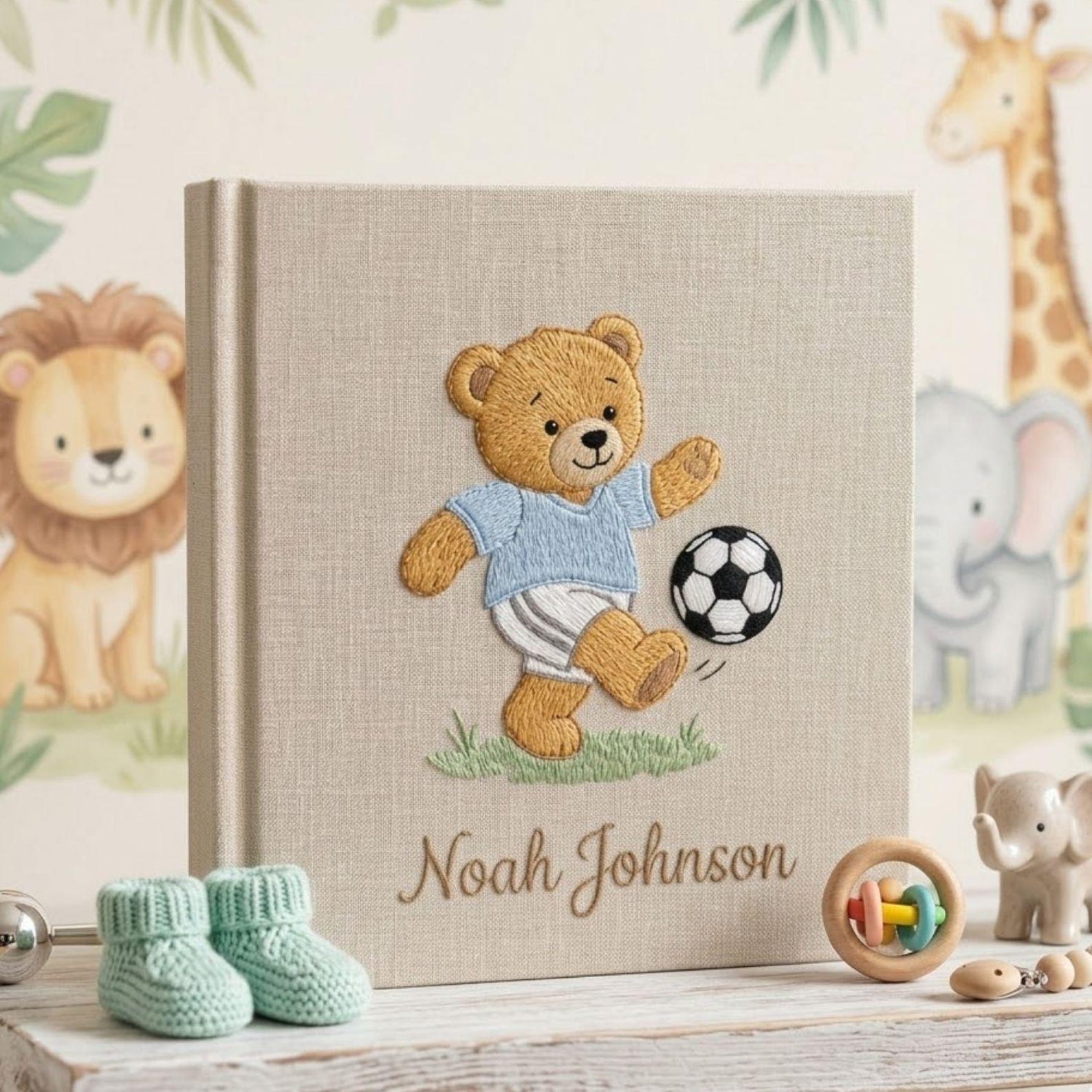 Personalized hand embroidered photo album featuring a teddy bear playing soccer with a football and custom baby name on linen cover