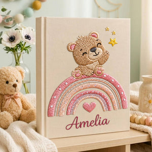 Personalized hand embroidered baby photo album featuring teddy bear sitting on pastel rainbow with stars and heart accents