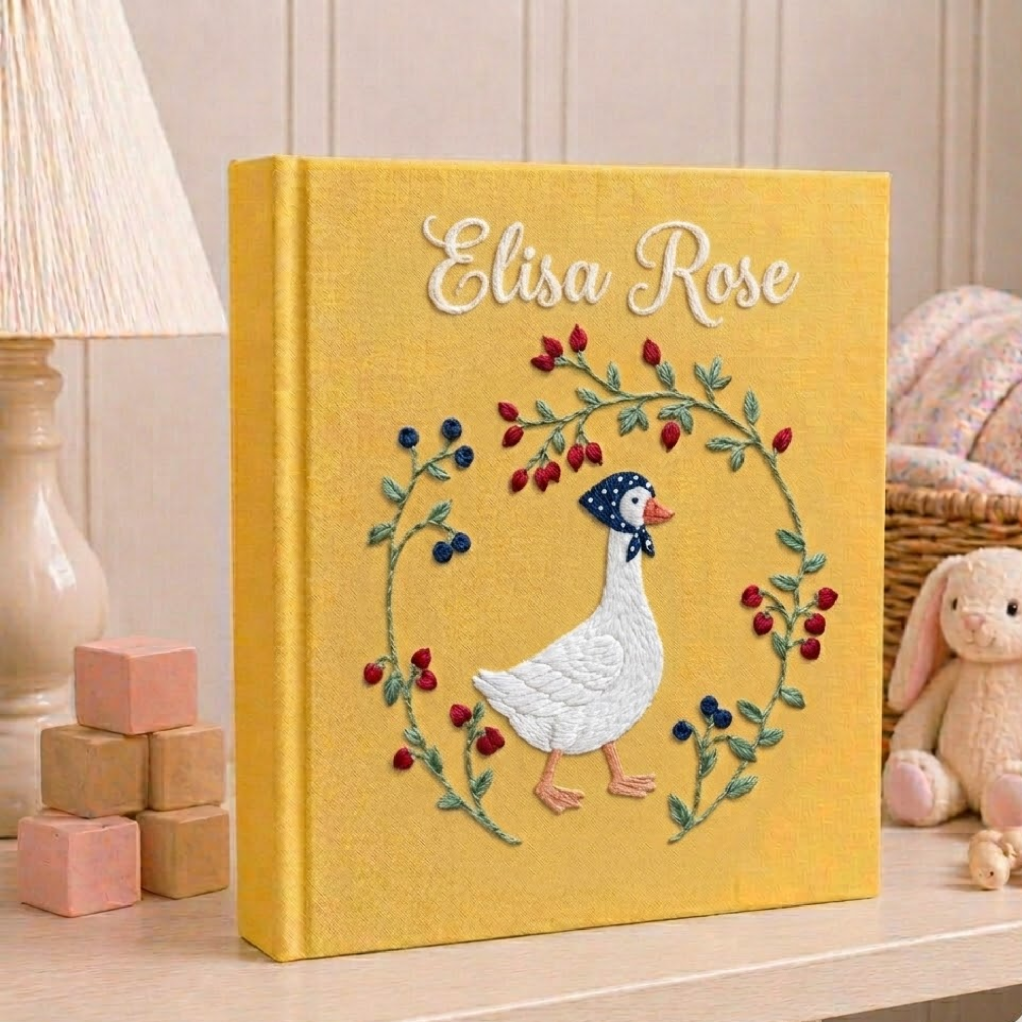 Personalized hand embroidered photo album featuring an elegant goose surrounded by a floral berry wreath on a golden linen cover