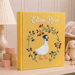 Personalized hand embroidered photo album featuring an elegant goose surrounded by a floral berry wreath on a golden linen cover
