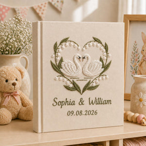 Personalized embroidered wedding photo album with swan heart embroidery, botanical wreath, custom names, wedding date, and linen hardcover design