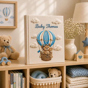 Personalized embroidered baby photo album featuring pilot teddy bear in blue hot air balloon with fluffy clouds