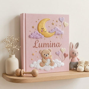 Personalized hand embroidered photo album featuring a teddy bear holding a baby bottle on fluffy clouds beneath a crescent moon with heart balloons and stars on a pink linen cover customized with a baby name