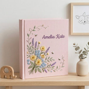 Personalized hand embroidered photo album featuring a wildflower bouquet with lavender, daisies, delicate greenery, bees, and custom name embroidery on a blue linen cover