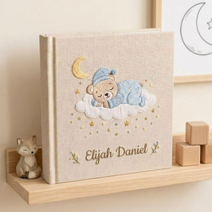 Personalized hand embroidered photo album featuring a sleeping teddy bear on a cloud beneath a crescent moon with custom name embroidery