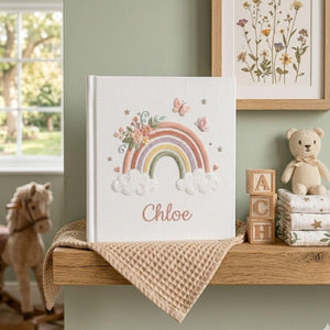 Custom embroidered baby photo album with pastel rainbow, butterflies, floral embroidery, fluffy clouds, and personalized name