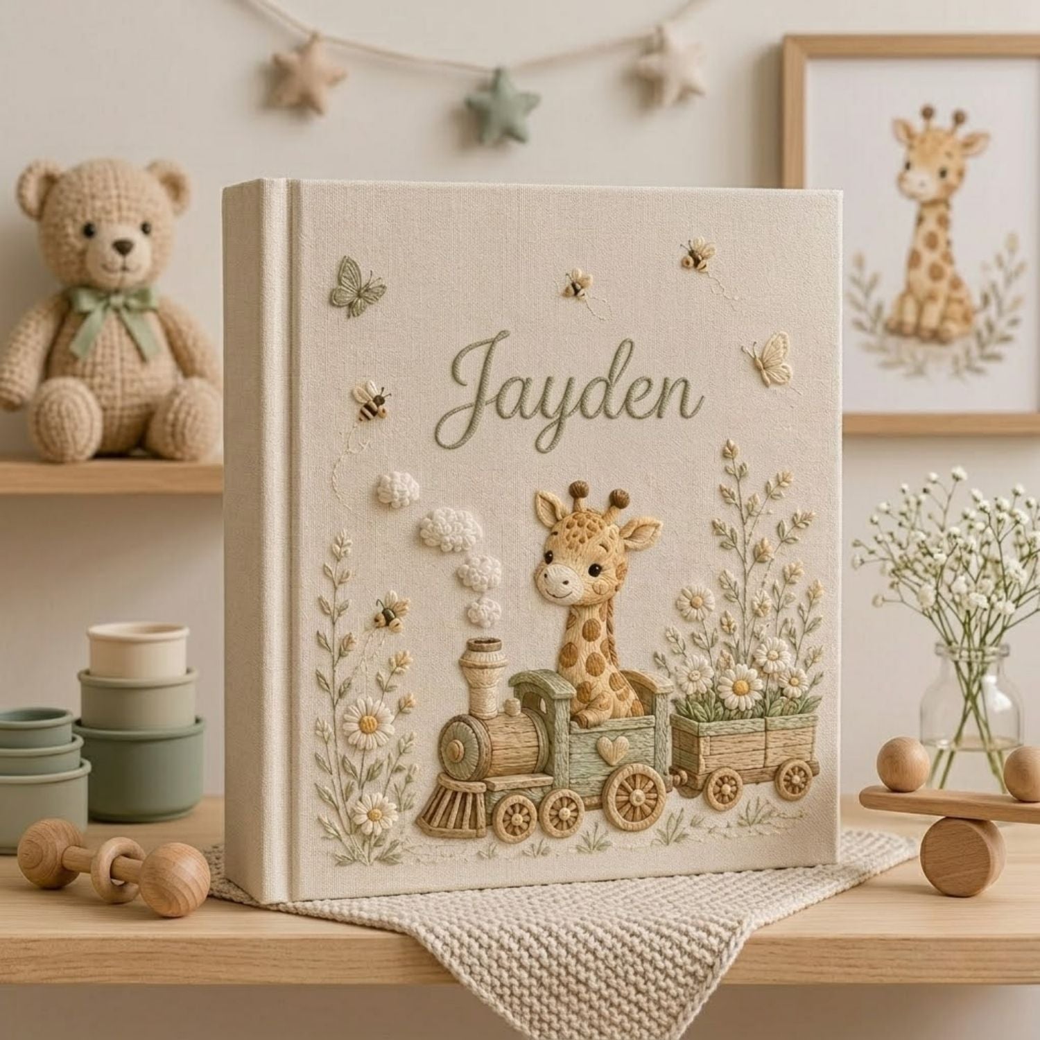 Personalized hand embroidered photo album featuring a baby giraffe riding a vintage train surrounded by daisies, butterflies, and honeybees on a premium linen cover customized with a baby name