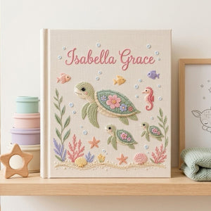 Personalized hand embroidered photo album featuring a sea turtle family with coral reefs, tropical fish, seashells, starfish, and seahorse on a premium linen cover customized with a baby name