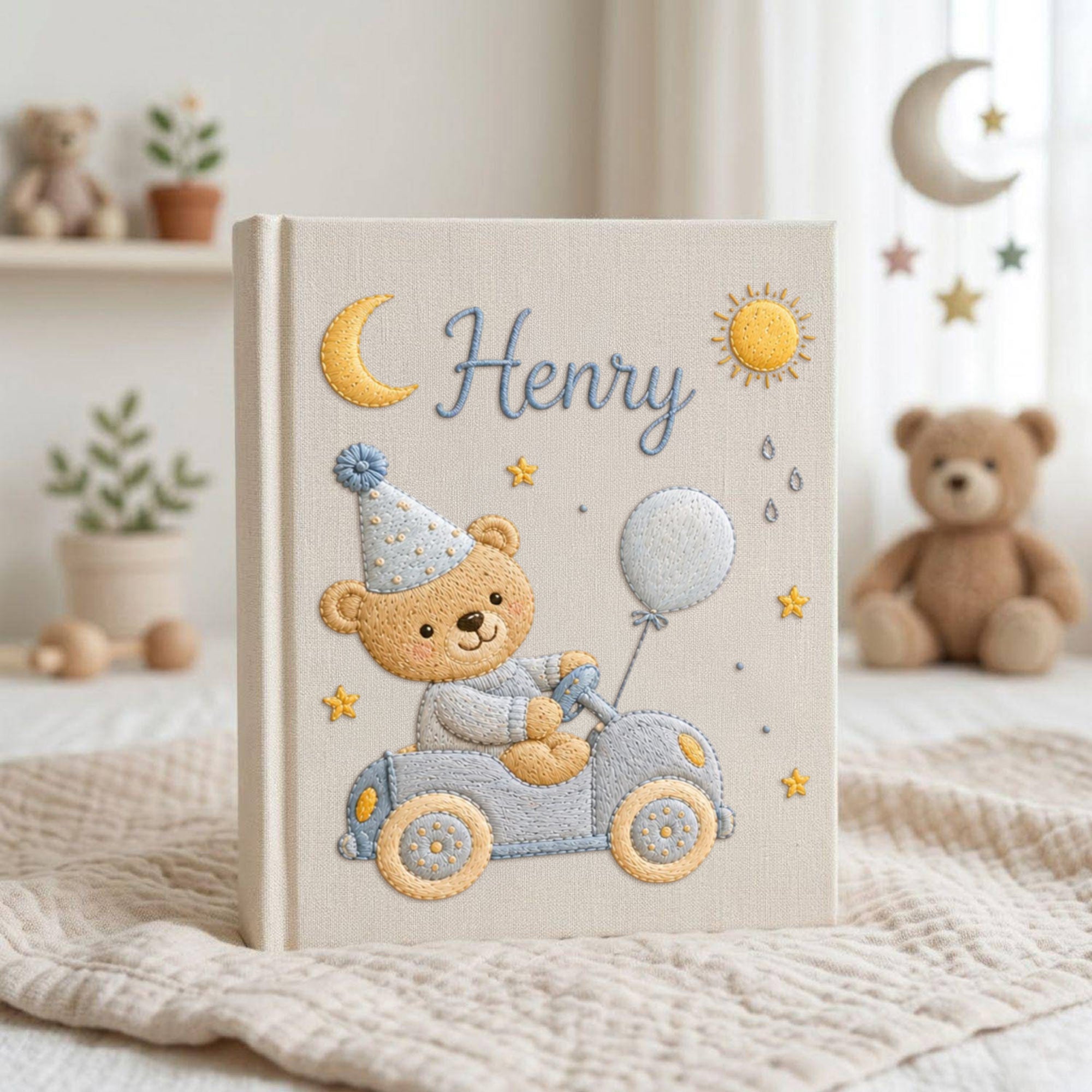 Personalized hand embroidered baby photo album featuring teddy bear driving a pastel blue vintage car with balloon, moon, stars, and sunshine accents