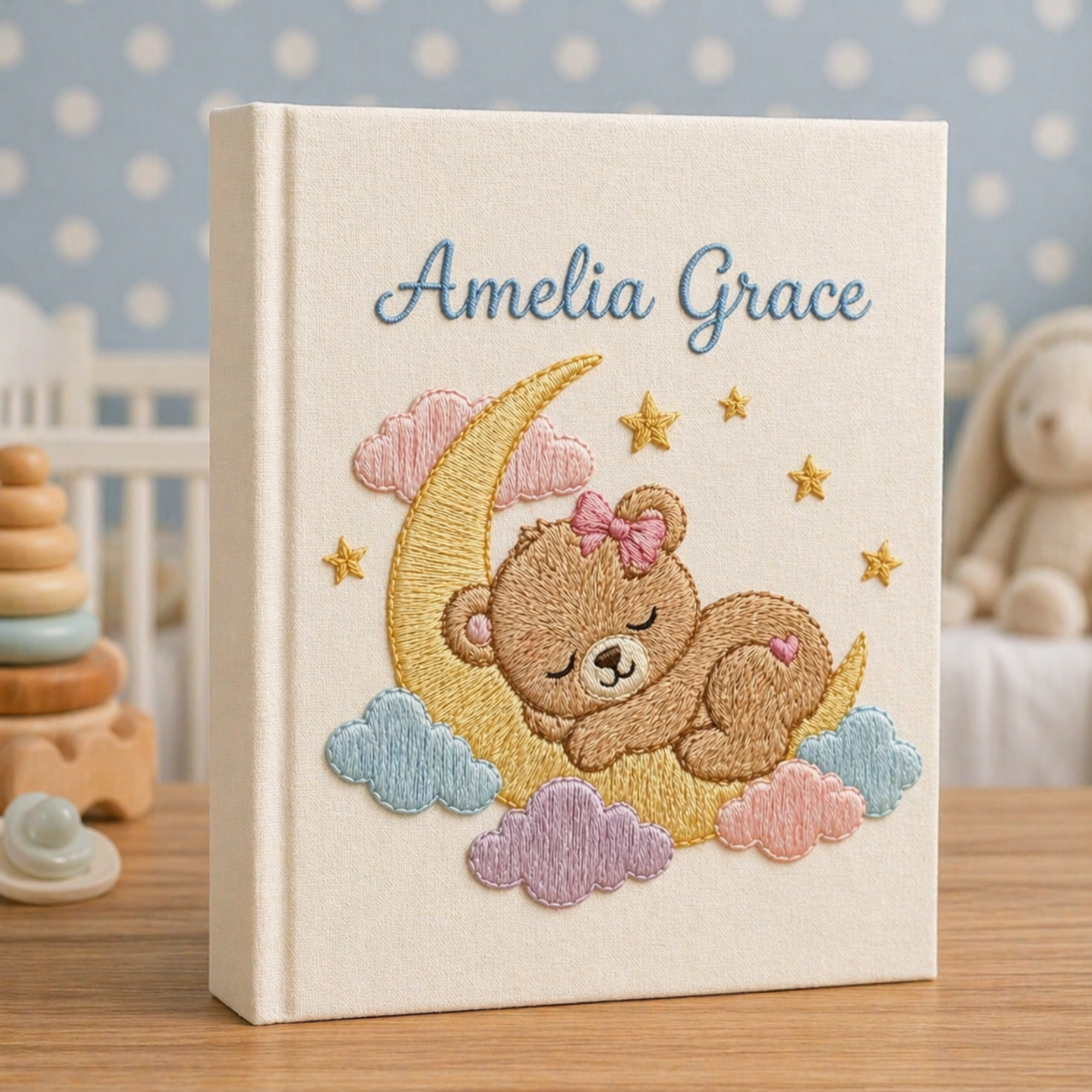 Personalized hand embroidered photo album featuring a dreamland night sky scene with crescent moon, sleeping teddy bear, stars, clouds and custom name embroidery