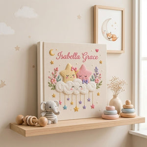 Personalized hand embroidered photo album featuring smiling stars resting on fluffy clouds with hanging pastel stars and floral accents on a premium linen cover customized with a baby name