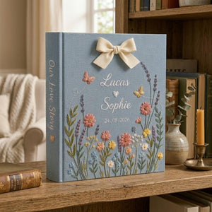 Personalized embroidered floral couple photo album with butterflies, custom names, ribbon bow, and romantic wildflower design on blue linen cover
