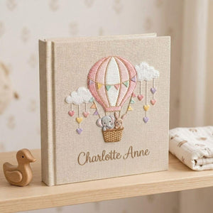 Personalized hand embroidered photo album featuring an elephant and bunny in a pastel hot air balloon with hanging hearts and custom name embroidery