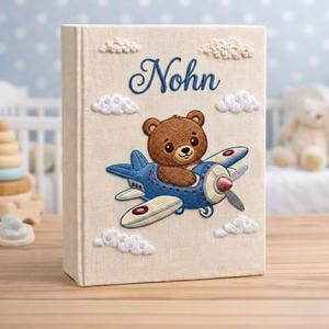 Personalized hand embroidered photo album featuring a teddy bear pilot flying a vintage airplane with clouds and stars