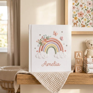 Custom embroidered baby photo album with pastel rainbow, butterflies, floral embroidery, fluffy clouds, and personalized name
